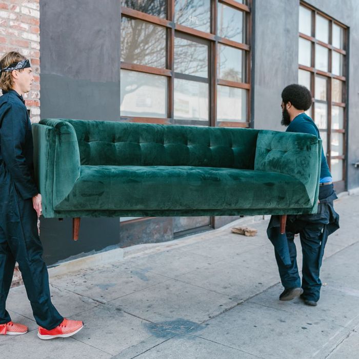 Two movers carrying a sofa along a street