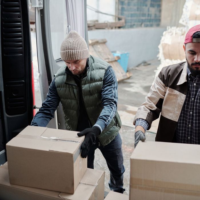 Two workers loading boxes into the back of a van